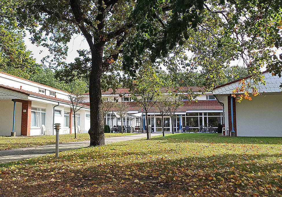 Wohn- und Pflegeheim mit Innenhof, Bäumen und Weg im Herbst