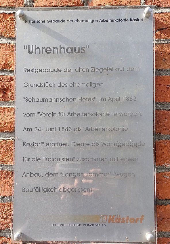 Hinweistafel Uhrenhaus mit erklärendem Text an roter Backsteinwand