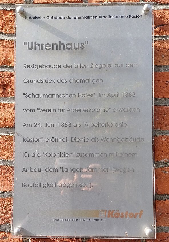 Hinweistafel Uhrenhaus mit erklärendem Text an roter Backsteinwand