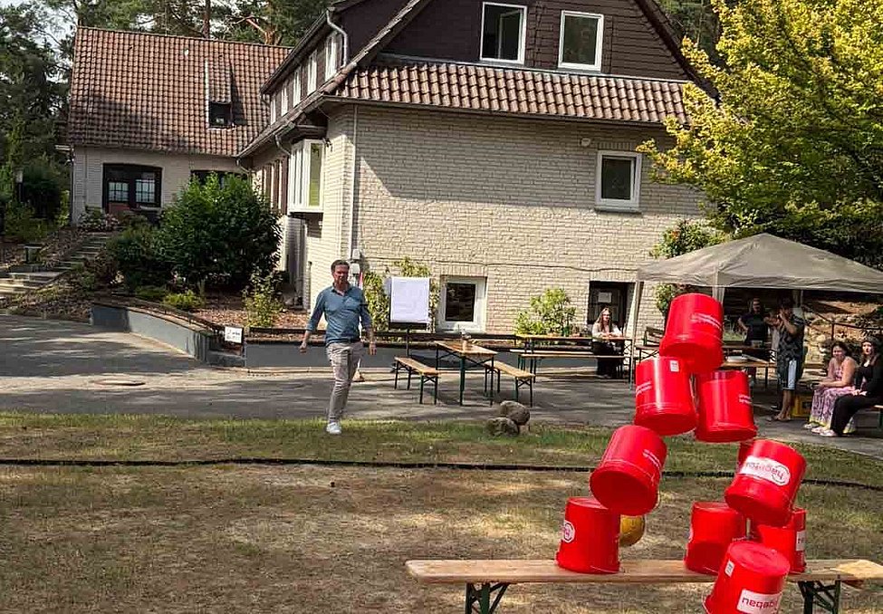 Mann schießt mit einem Ball auf mehrere rote Eimer