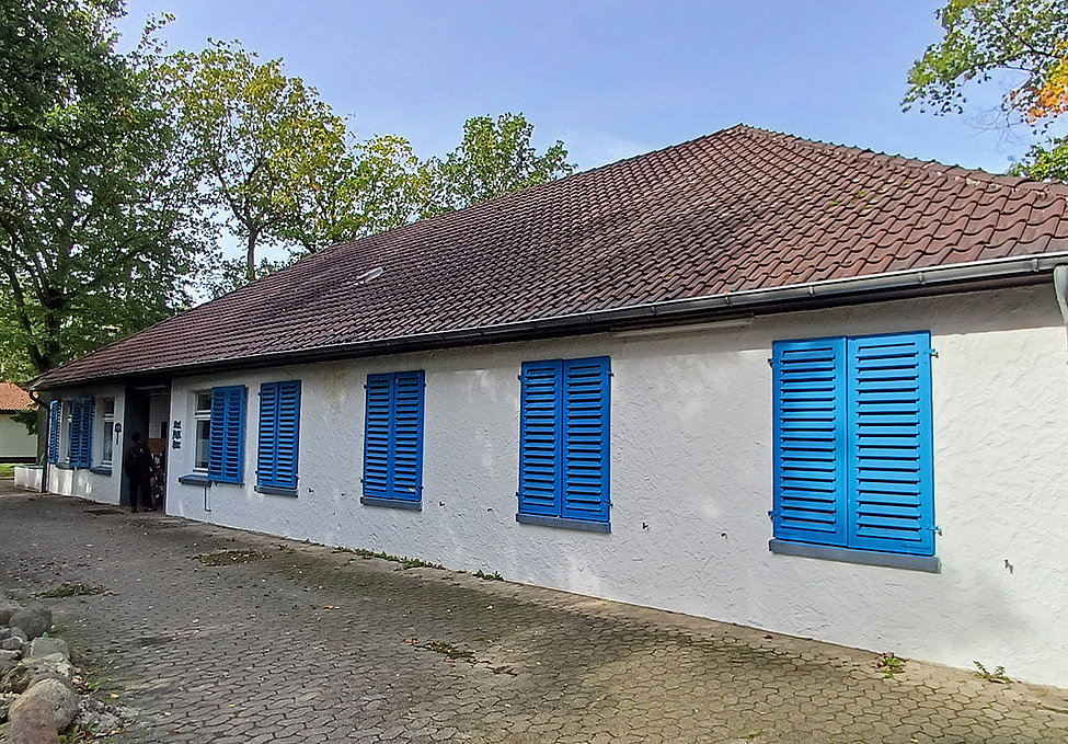 Karl-Fiesel-Haus mit weißen Wänden und blauen Fensterläden