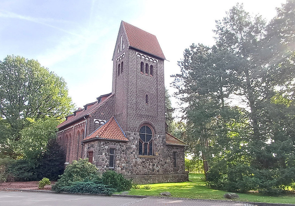 Backsteinkirche mit Turm und Bäumen in Kästorf